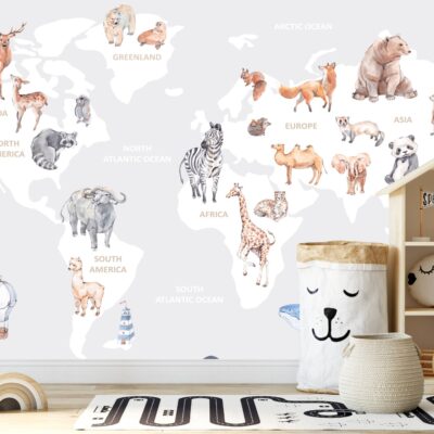 Pokój dziecięcy na pierwszym planie przytulne zabawki i drewniany regał, na ścianie fototapeta z mapą świata. białe kontynenty na który przedstawione są gatunki zwierząt występujące w danym regionie.