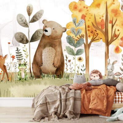 Fototapeta ścienna dla dzieci przedstawiająca przyjazne leśne zwierzęta: młodego jelenia, dużego brązowego misia, żabę i zajączka, stojących na trawiastym tle z różnorodnymi roślinami i grzybkami. Z prawej strony widoczne są drzewa z jesiennymi, żółto-pomarańczowymi liśćmi oraz sowa siedząca na gałęzi. W tle delikatny, akwarelowy las w pastelowych odcieniach. Na pierwszym planie drewniane łóżko-domek z kocami i poduszkami w ciepłych, ziemistych barwach, oraz pluszowe zabawki, w tym jeż i wieloryb.