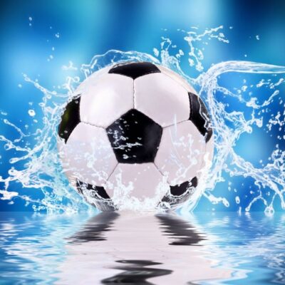 Fototapeta do pokoju dziecięcego przedstawiająca piłkę nożną spadającą do wody. Na niebieskim tle rozpryskują sie krople wody