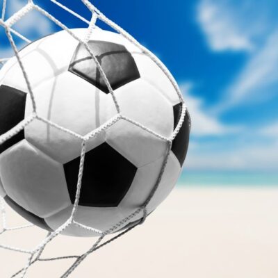 Fototapeta do pokoju chłopca przedstawiająca piłkę nożną w siatce bramki na tle nieba