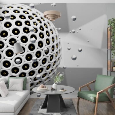 Fototapeta 3D w nowoczesnym salonie przedstawiająca wielką, białą kulę z regularnymi otworami oraz mniejsze, lewitujące kule na geometrycznym tle po lewej stronie biała kanapa na środku stolik a po prawej zielony fotel. Za fotelem regał.