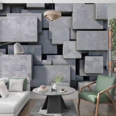 Obrazek przedstawia Aranżację salonu z geometryczną tapetą 3D imitującą surowy beton. Wielkoformatowa grafika z wypukłymi prostopadłościanami tworzy efekt głębi na ścianie za jasnoszarą kanapą i nowoczesnym regałem z roślinami.